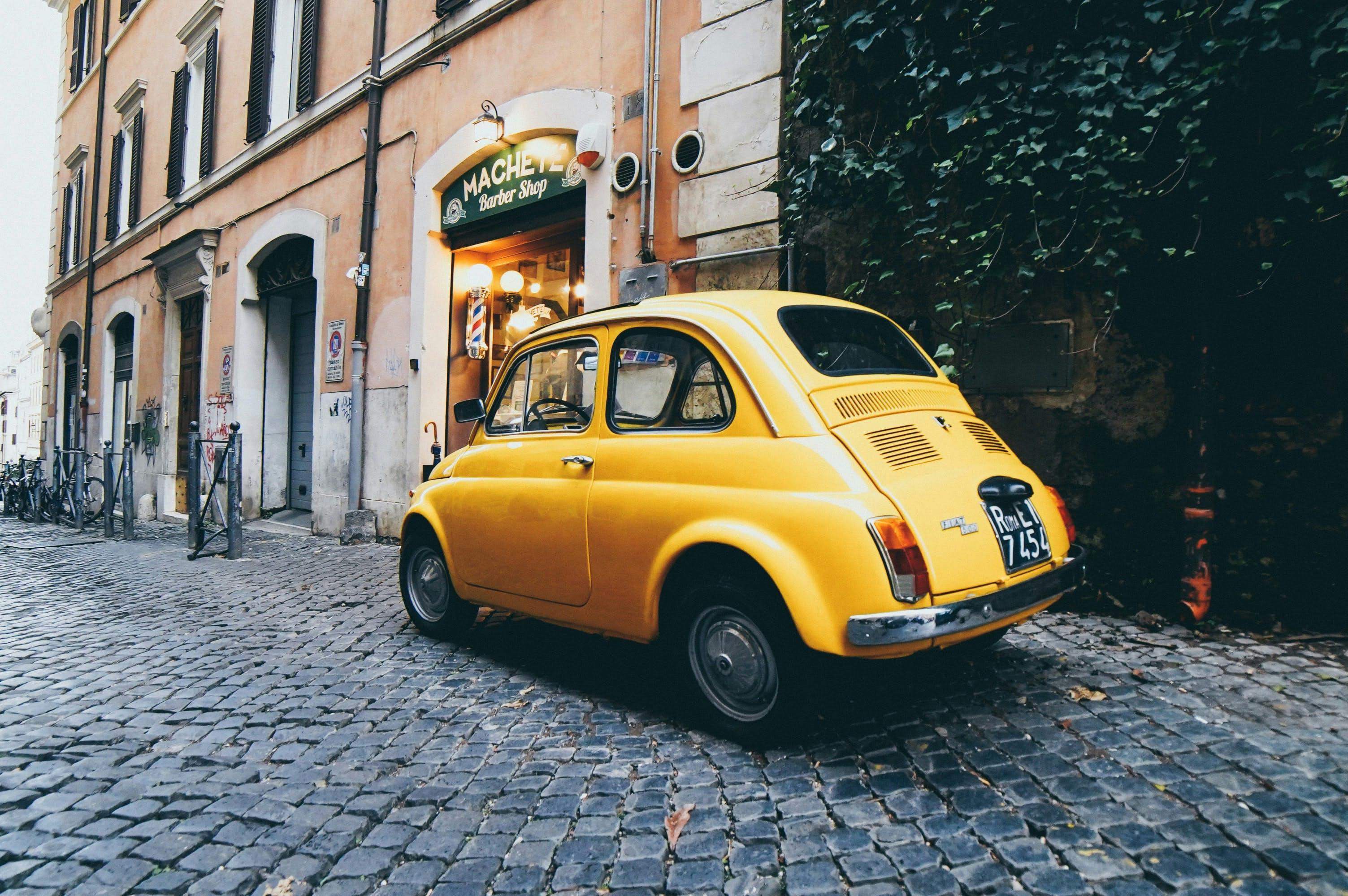 An old-fashioned yellow car parked in a street in Rome